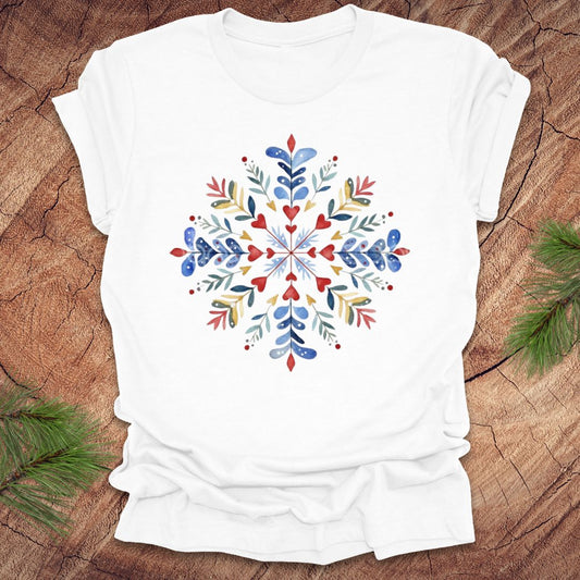 White t-shirt with a colorful snowflake and floral design on a wooden surface