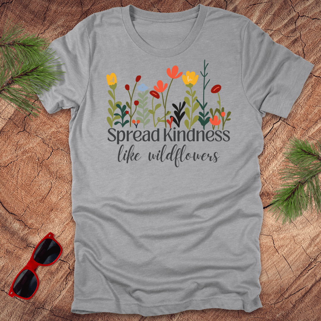 Gray t-shirt with floral design and 'Spread Kindness like wildflowers' text on a wooden surface with sunglasses.