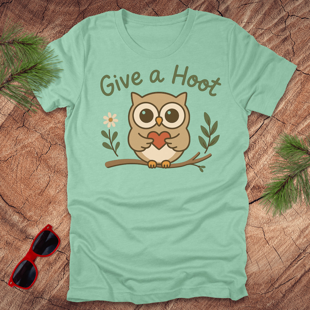 Mint green t-shirt with an owl graphic and 'Give a Hoot' text on a wooden surface.