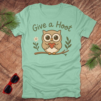 Mint green t-shirt with an owl graphic and 'Give a Hoot' text on a wooden surface.