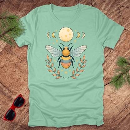 Mint green tshirt with a bee and moon graphic on a wood background.