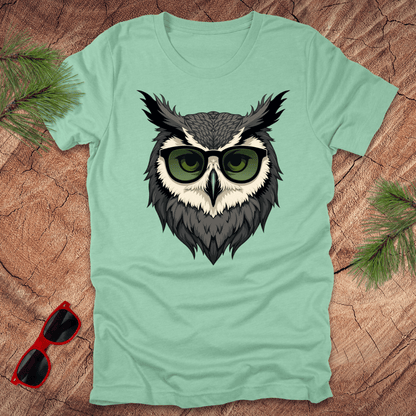 Mint green tshirt with a graphic of an owl head with sunglasses on. it is on a wood background.