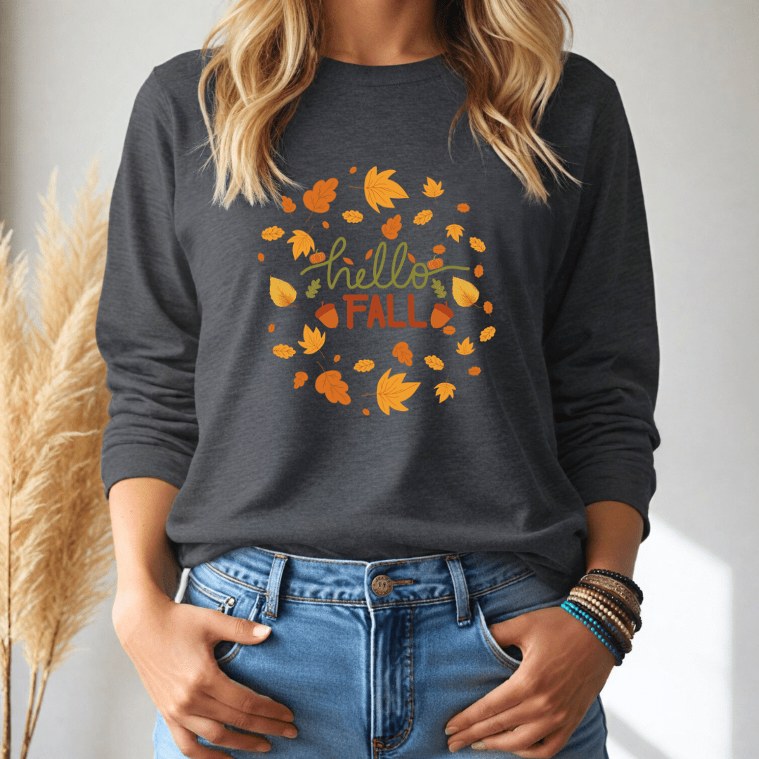 Person wearing a dark gray long sleeve tshirt with 'hello FALL' and leaf design, standing against a neutral background.