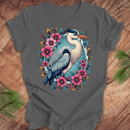 Gray t-shirt with a heron and floral design on a wood background.