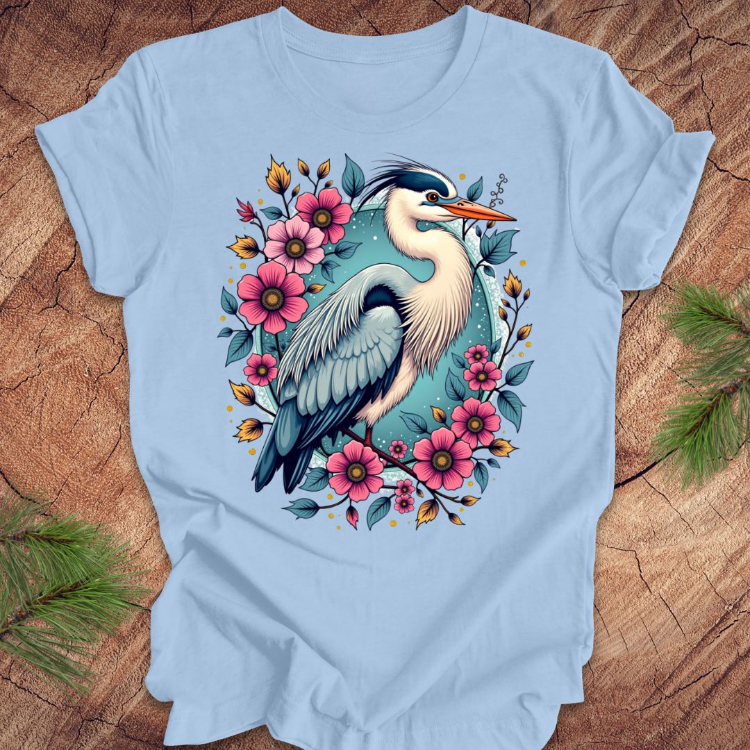 Blue t-shirt with a heron and floral design on a wood background.