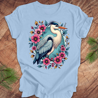 Blue t-shirt with a heron and floral design on a wood background.