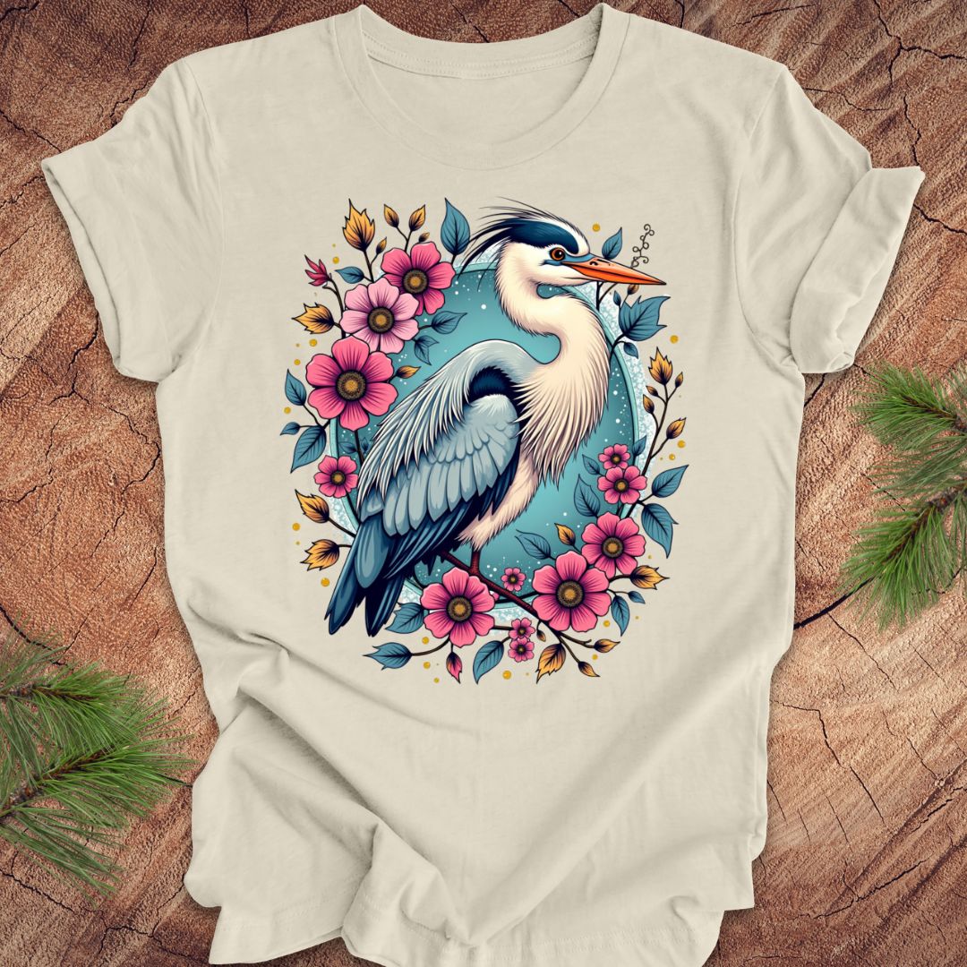 Beige t-shirt with a heron and floral design on a wood background.