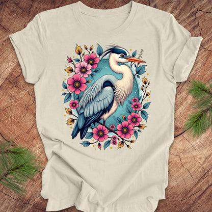 Beige t-shirt with a heron and floral design on a wood background.