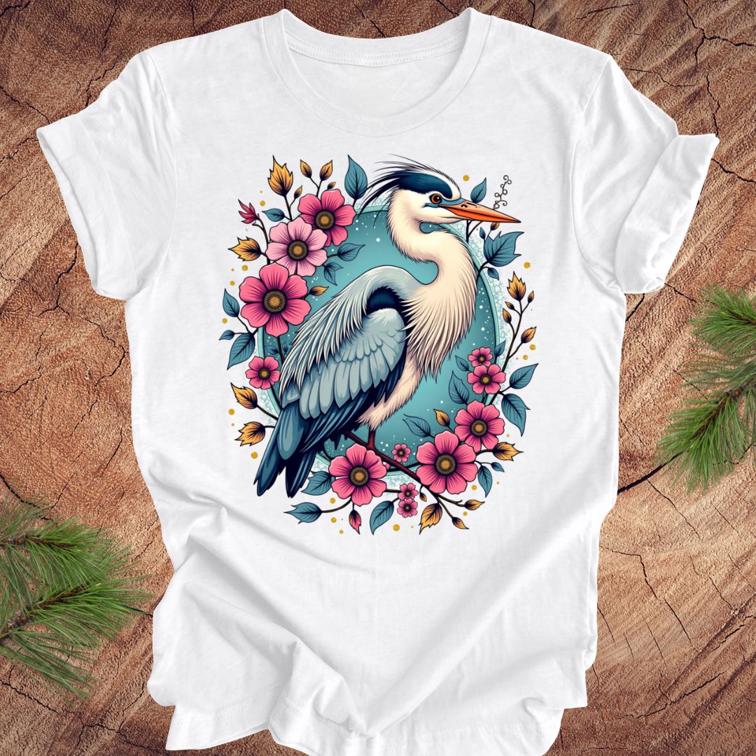 White t-shirt with a heron and floral design on a wood background.