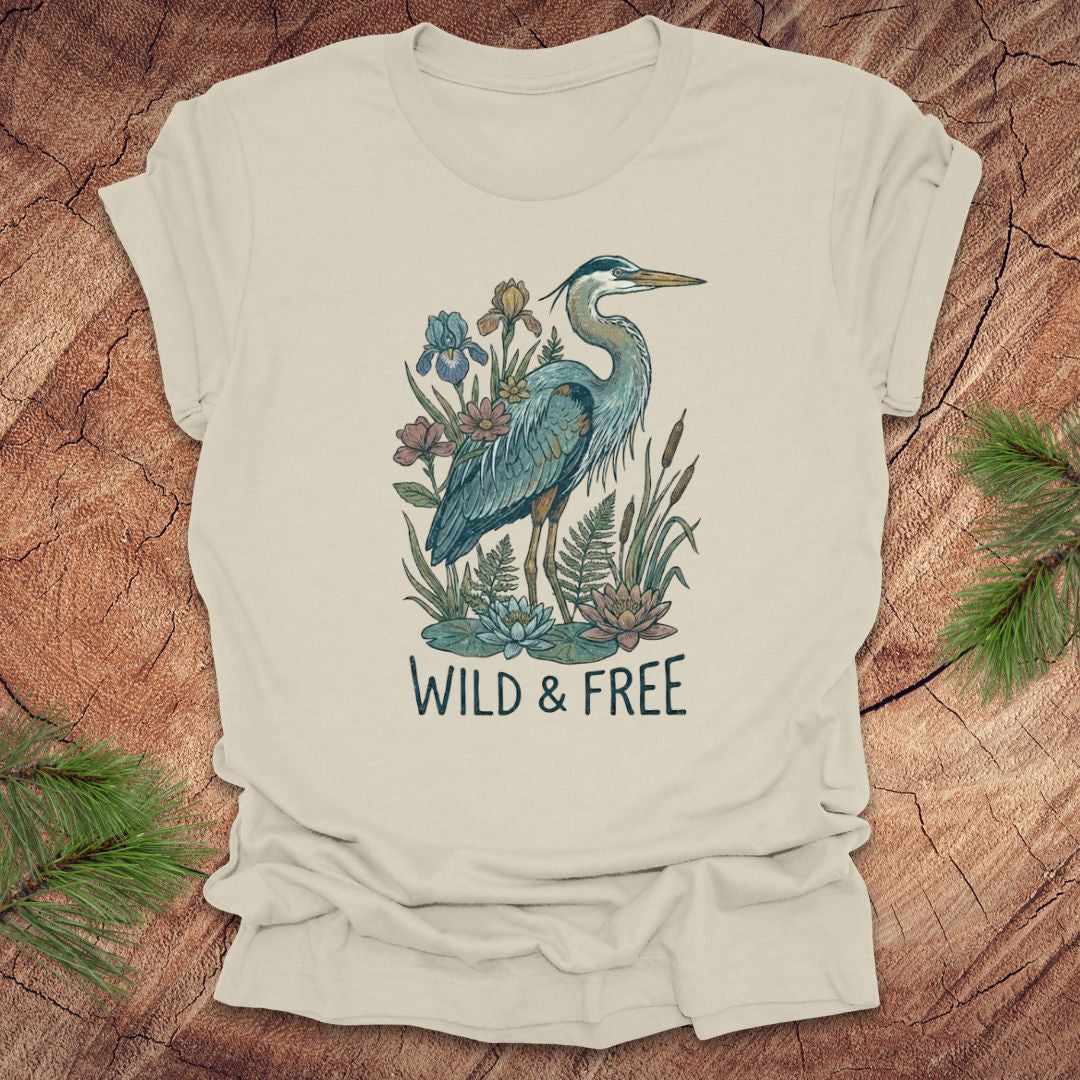 Beige t-shirt with a heron and floral design with text, 'wild and free' on a wooden surface