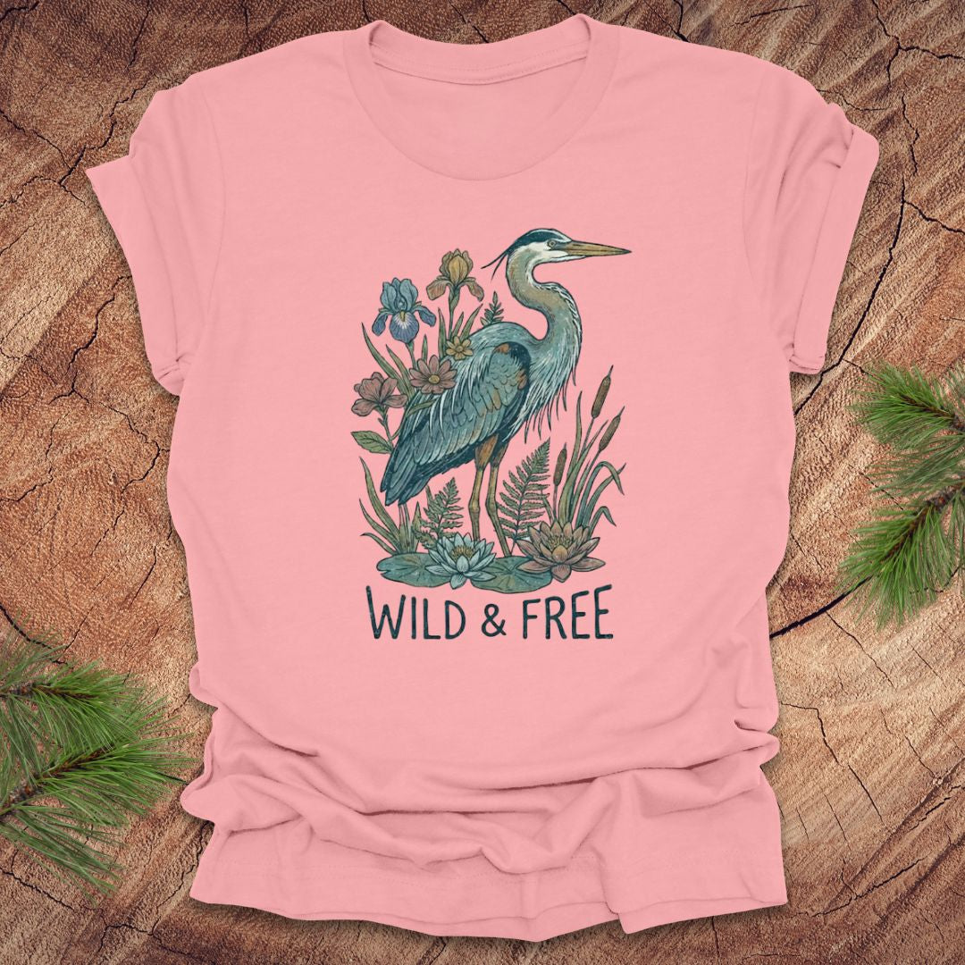 Pink t-shirt with a heron and floral design with text, 'wild and free' on a wooden surface