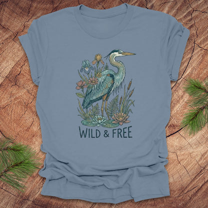 Steel blue t-shirt with a heron and floral design with text, 'wild and free' on a wooden surface