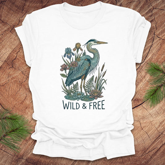 White t-shirt with a heron and floral design with text, 'wild and free' on a wooden surface