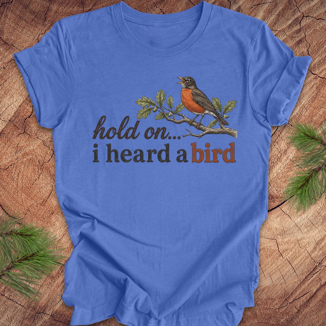Blue t-shirt with a bird graphic and text on a wooden surface