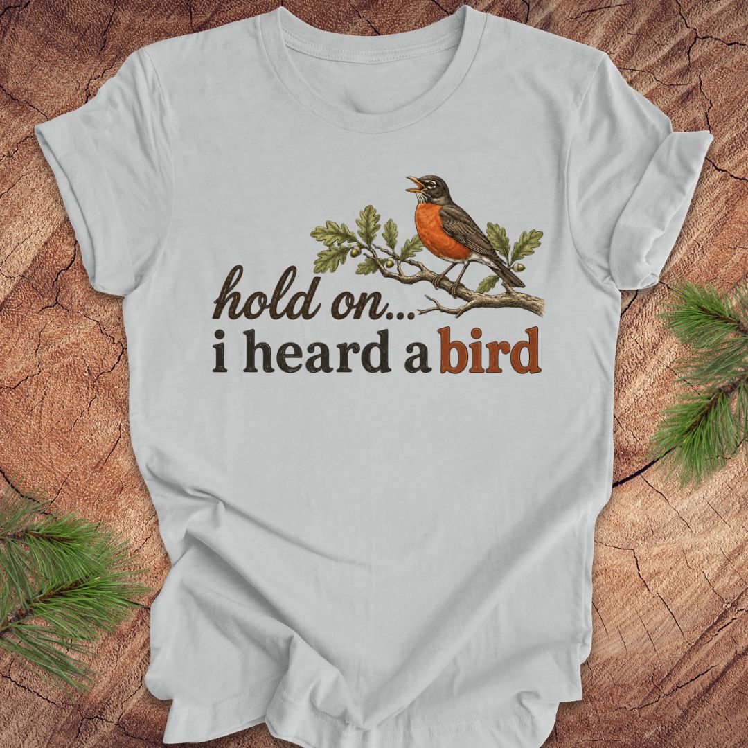 Gray t-shirt with a bird graphic and text on a wooden surface