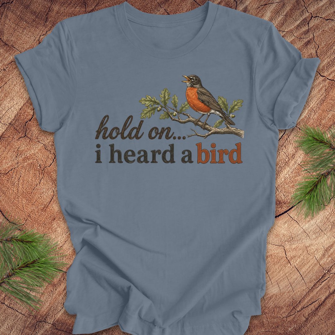 Blue t-shirt with a bird graphic and text on a wooden background