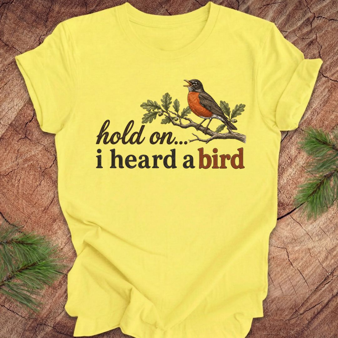 Yellow t-shirt with a bird graphic and text on a wooden surface