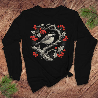Black long-sleeve tshirt with a chickadee and holly berry design on a wooden surface