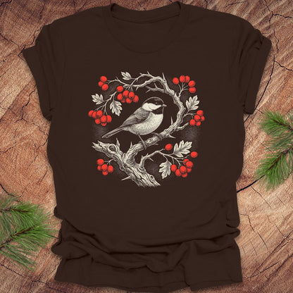 Brown t-shirt with a chickadee and holly  berry design on a wooden surface