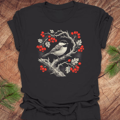 Dark gray t-shirt with a chickadee and holly  berry design on a wooden surface