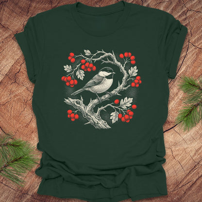 Green t-shirt with a chickadee and holly  berry design on a wooden surface
