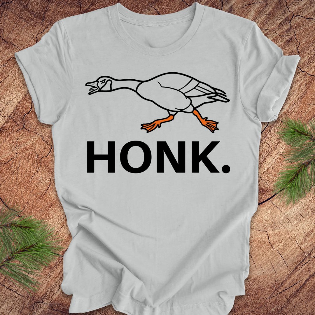 Gray t-shirt with a goose graphic and 'HONK.' text on a wooden surface.