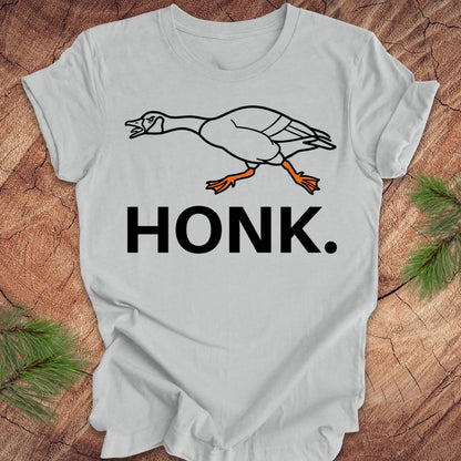 Gray t-shirt with a goose graphic and 'HONK.' text on a wooden surface.