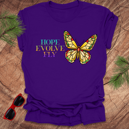 Purple t-shirt with a butterfly graphic and motivational text on a wooden surface.