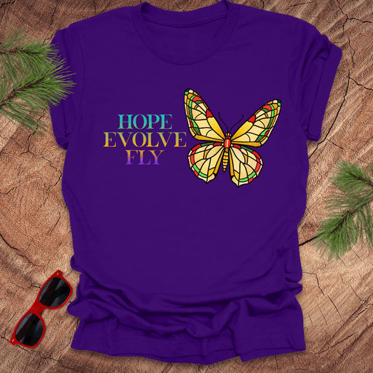 Purple t-shirt with a butterfly graphic and motivational text on a wooden surface.