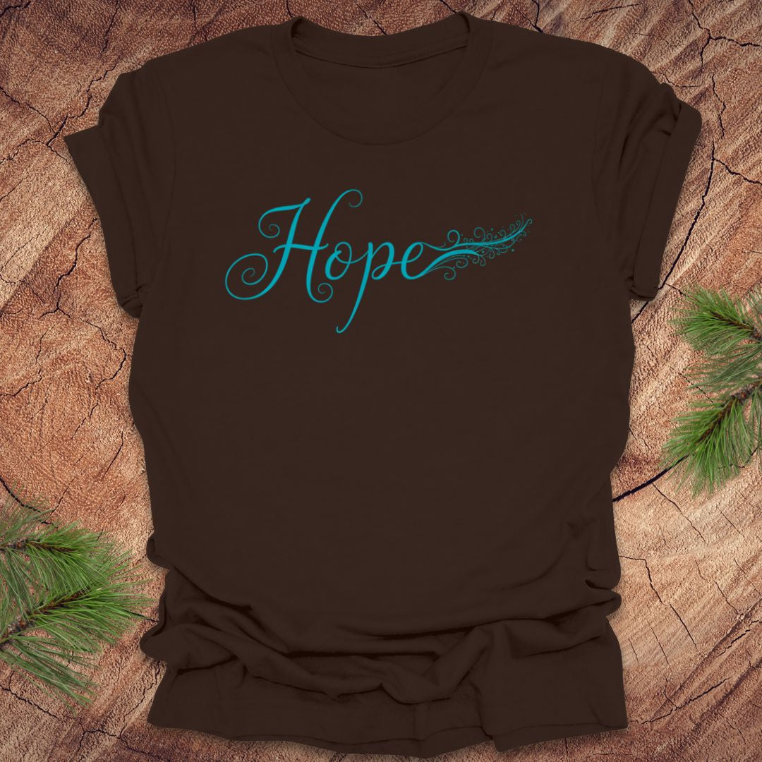 Brown t-shirt with hand drawn text, 'Hope' in turquoise on a wooden surface with greenery.