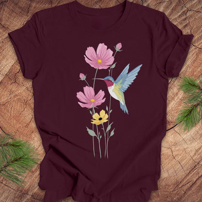 Maroon t-shirt with a colorful hummingbird and flower design on a wooden surface.