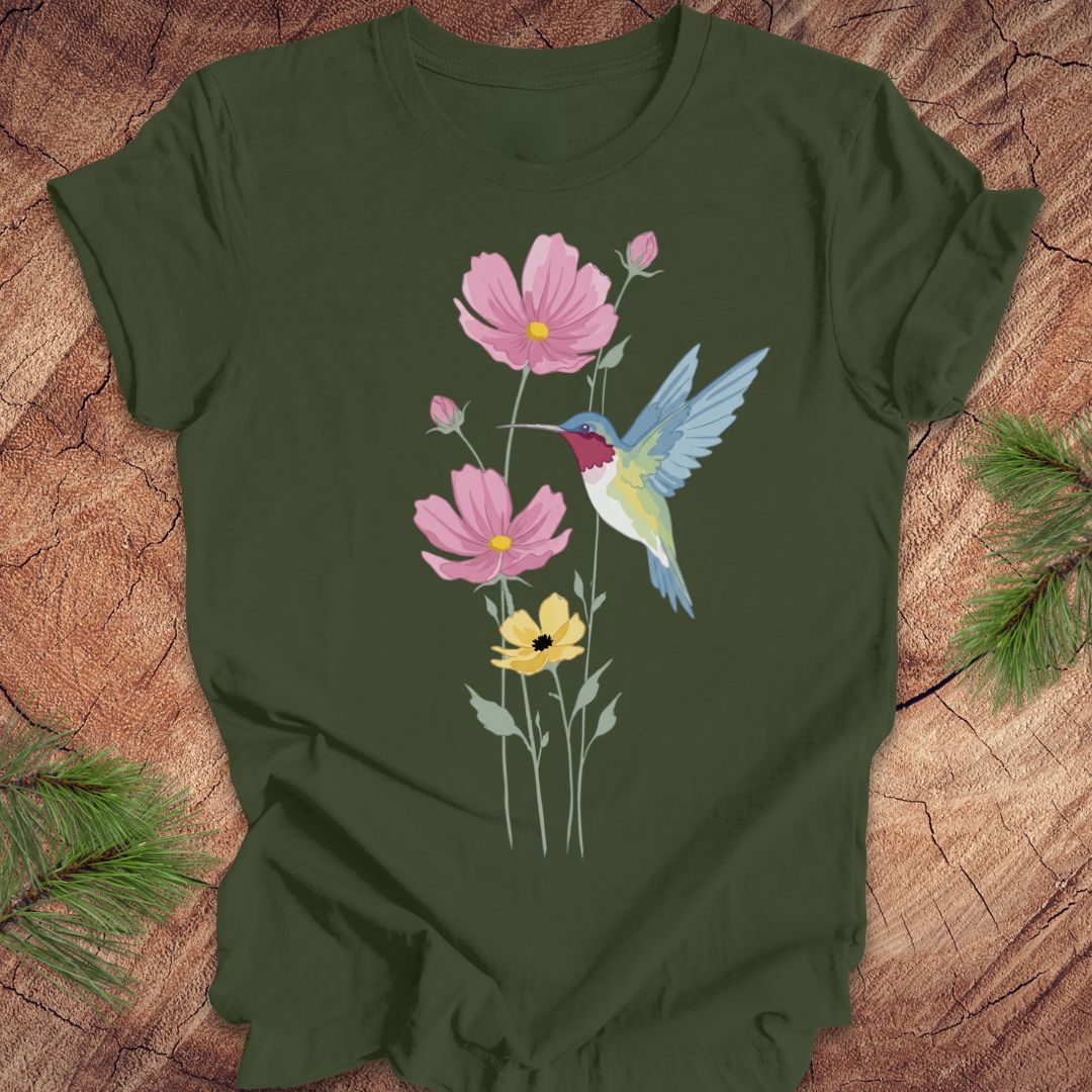 Green t-shirt with a colorful hummingbird and flower design on a wooden surface.