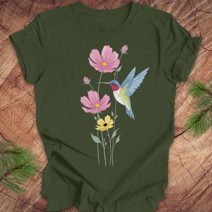 Green t-shirt with a colorful hummingbird and flower design on a wooden surface.