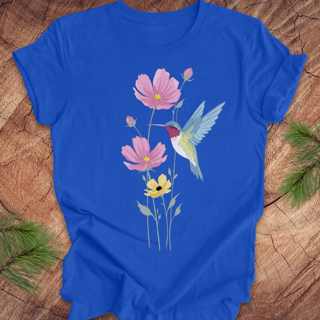Blue t-shirt with a hummingbird and flower design on a wooden surface