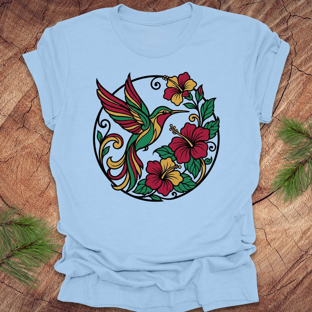 Light blue t-shirt with a colorful hummingbird and floral design on a wooden surface.