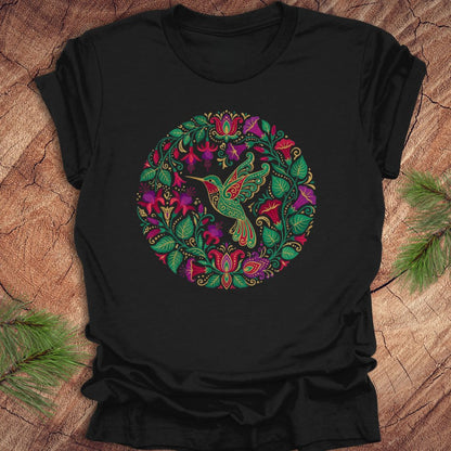 Black t-shirt with a colorful hummingbird and floral design on a wooden surface.