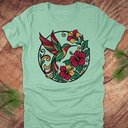 Light green t-shirt with a colorful hummingbird and floral design on a wooden surface.