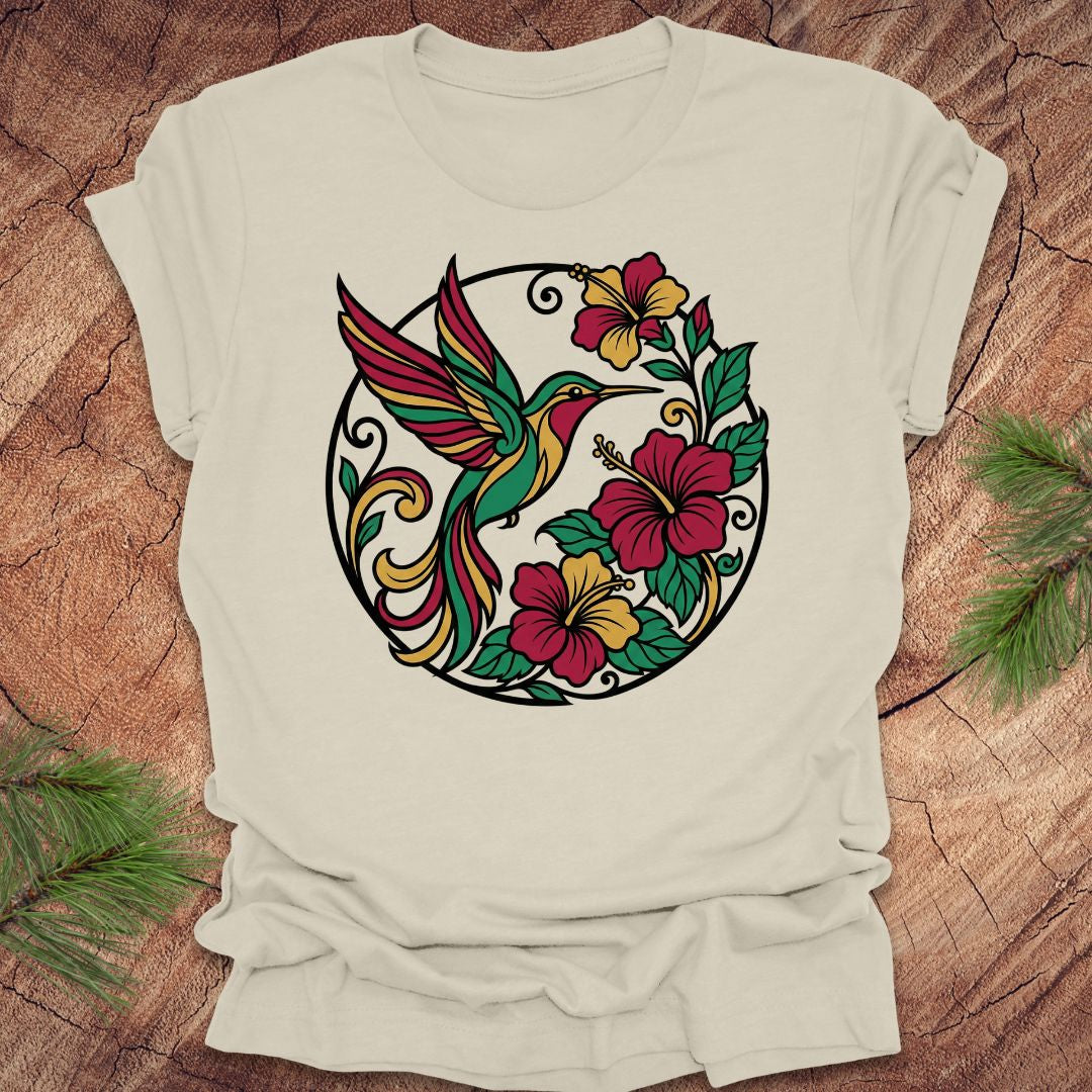 Beige t-shirt with a colorful hummingbird and floral design on a wooden surface.