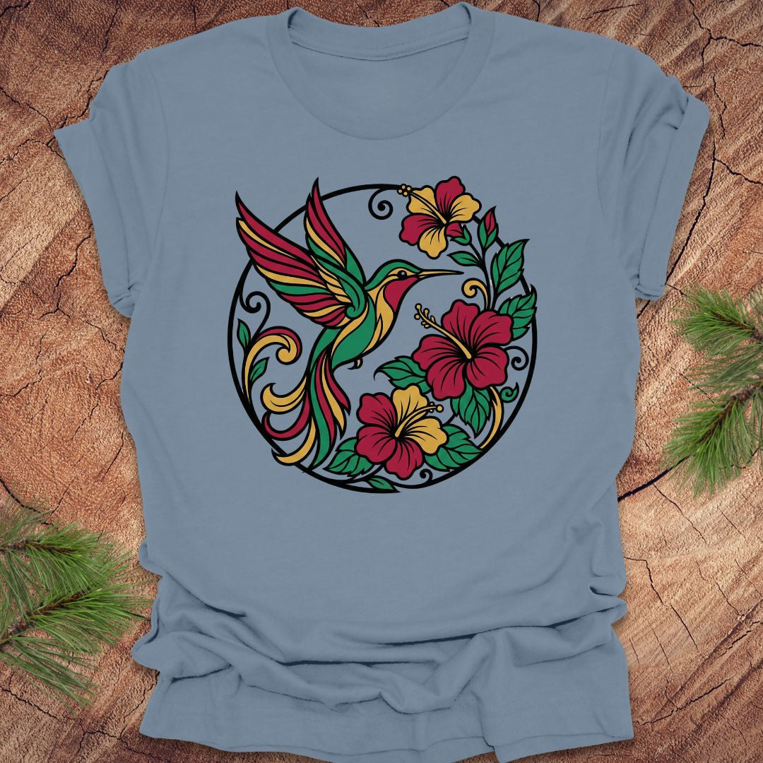 Blue t-shirt with a colorful hummingbird and floral design on a wooden surface.