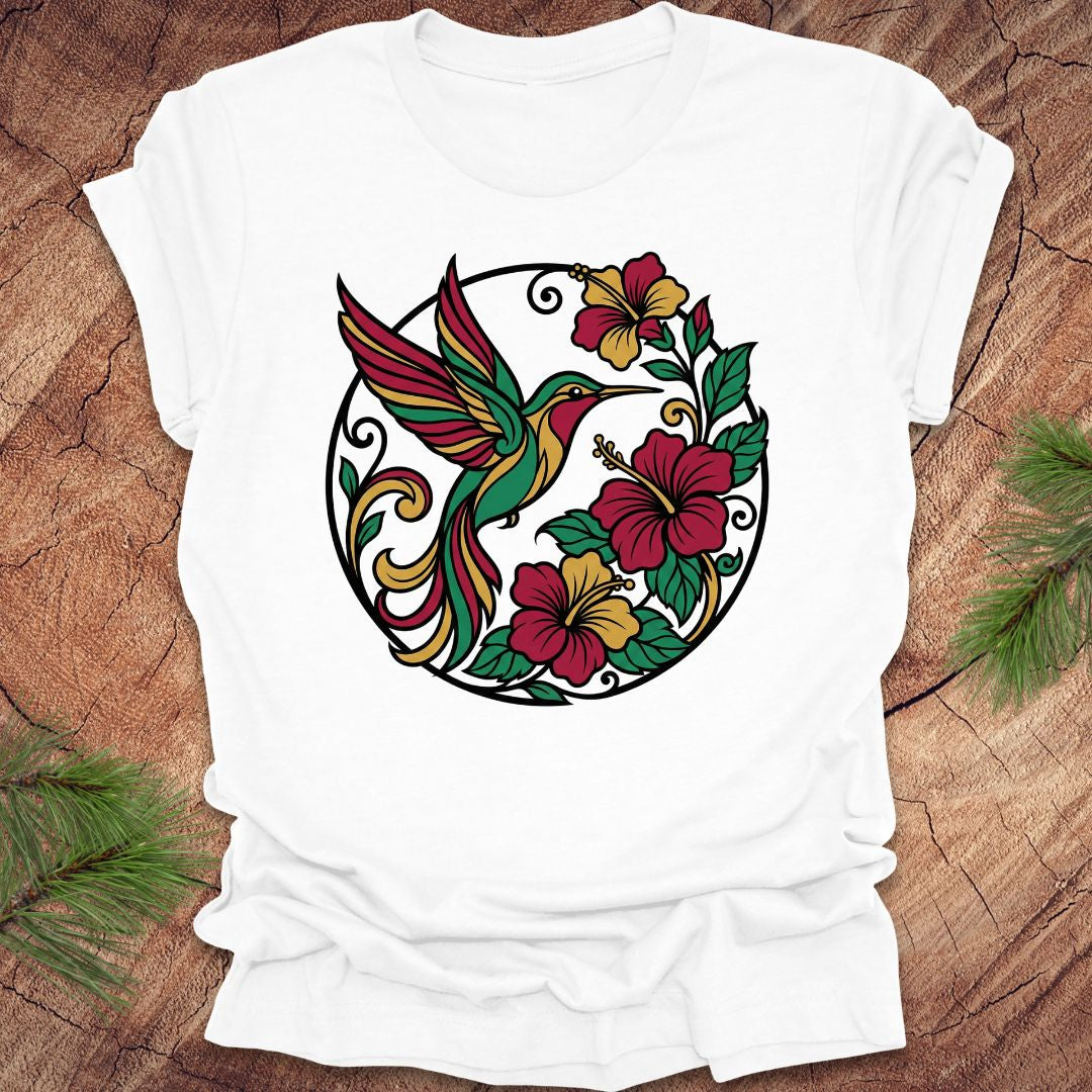 White t-shirt with a colorful hummingbird and floral design on a wooden surface.