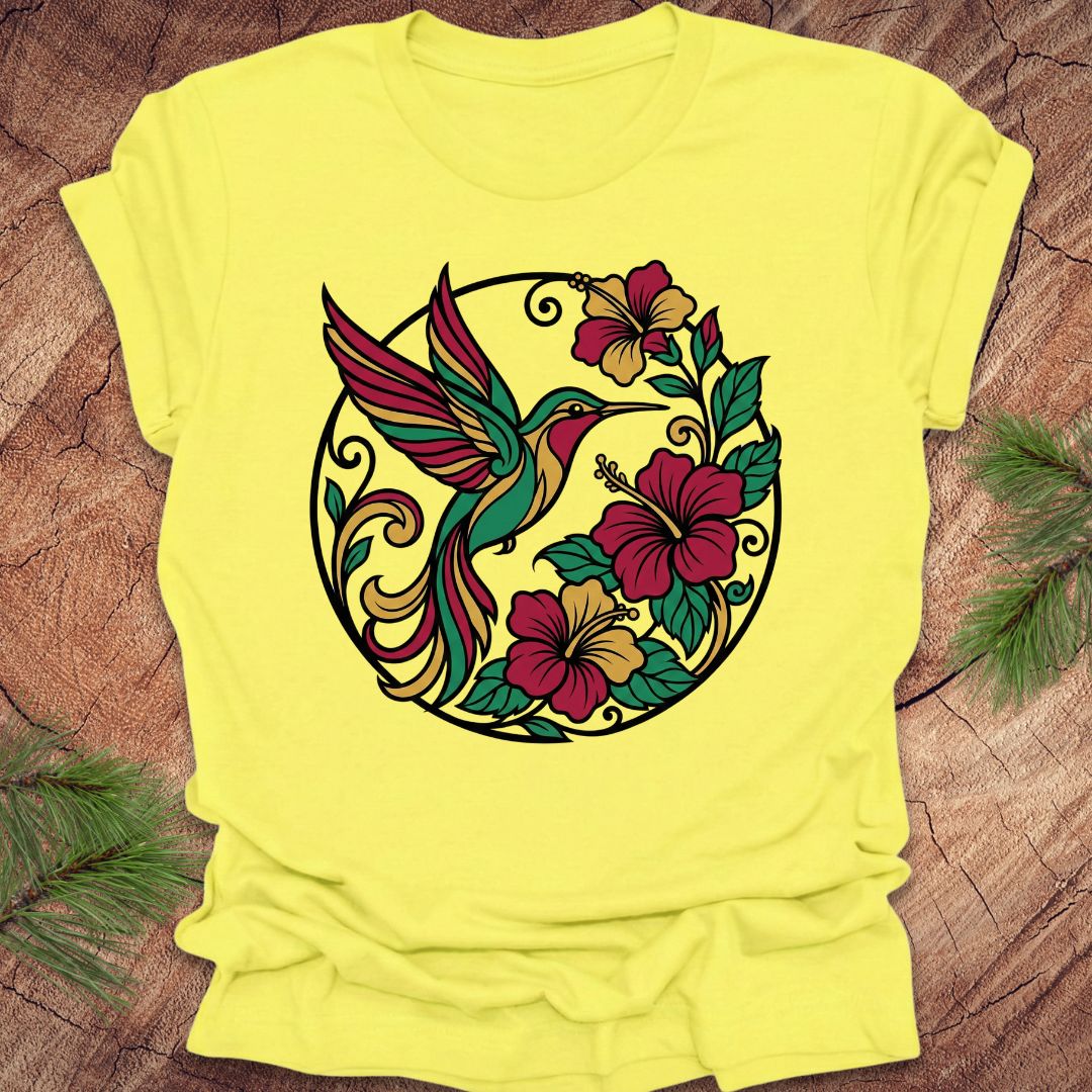 Yellow t-shirt with a colorful hummingbird and floral design on a wooden surface.