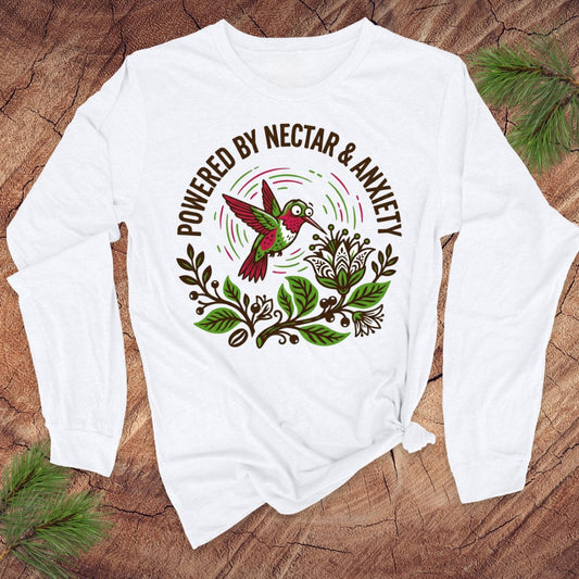 White long-sleeve shirt with a colorful hummingbird graphic and text on a wooden surface