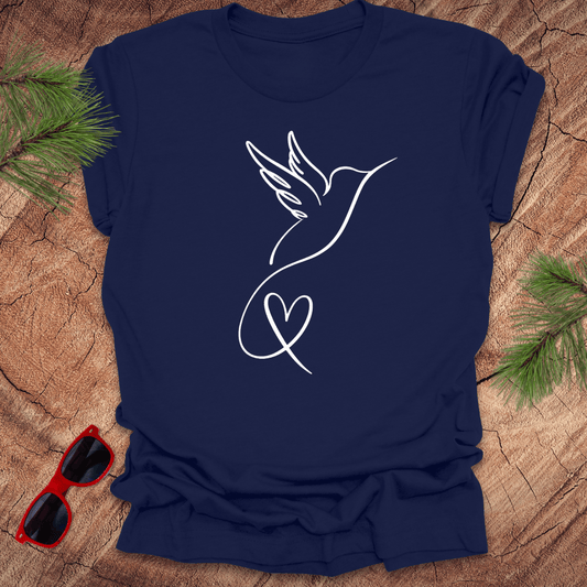 Navy blue t-shirt with a hummingbird and heart design on a wooden surface with sunglasses and greenery.