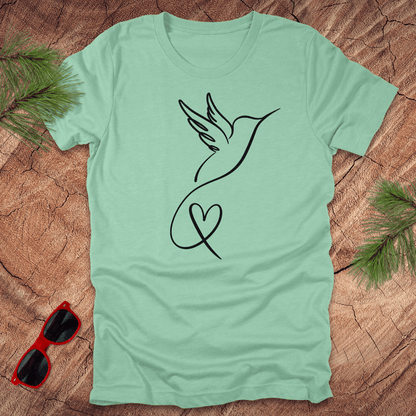 Mint green t-shirt with hummingbird and heart design on a wooden surface with sunglasses and greenery.