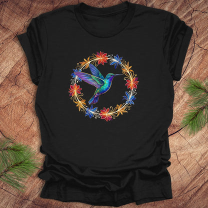 Black t-shirt with a colorful hummingbird and floral design on a wooden surface.