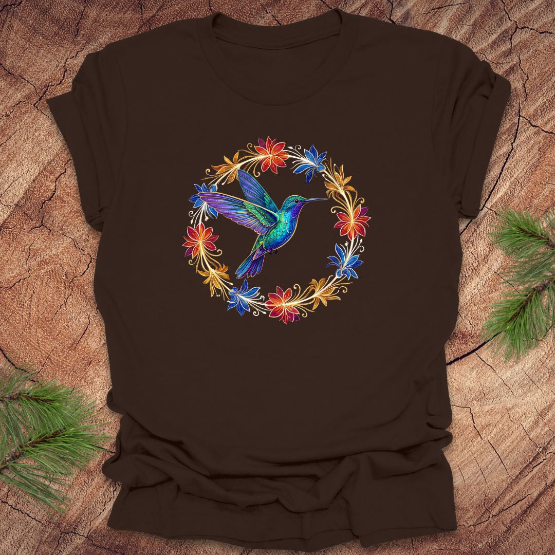 Brown t-shirt with a colorful hummingbird and floral design on a wooden surface.