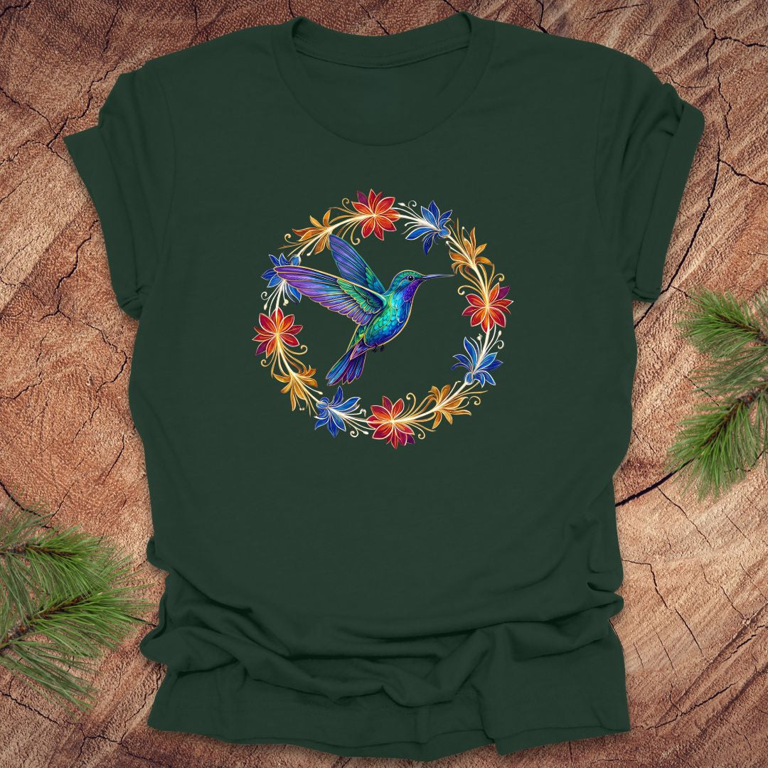 Green t-shirt with a colorful hummingbird and floral design on a wooden surface.