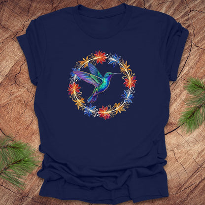 Navy blue t-shirt with a colorful hummingbird and floral design on a wooden surface.