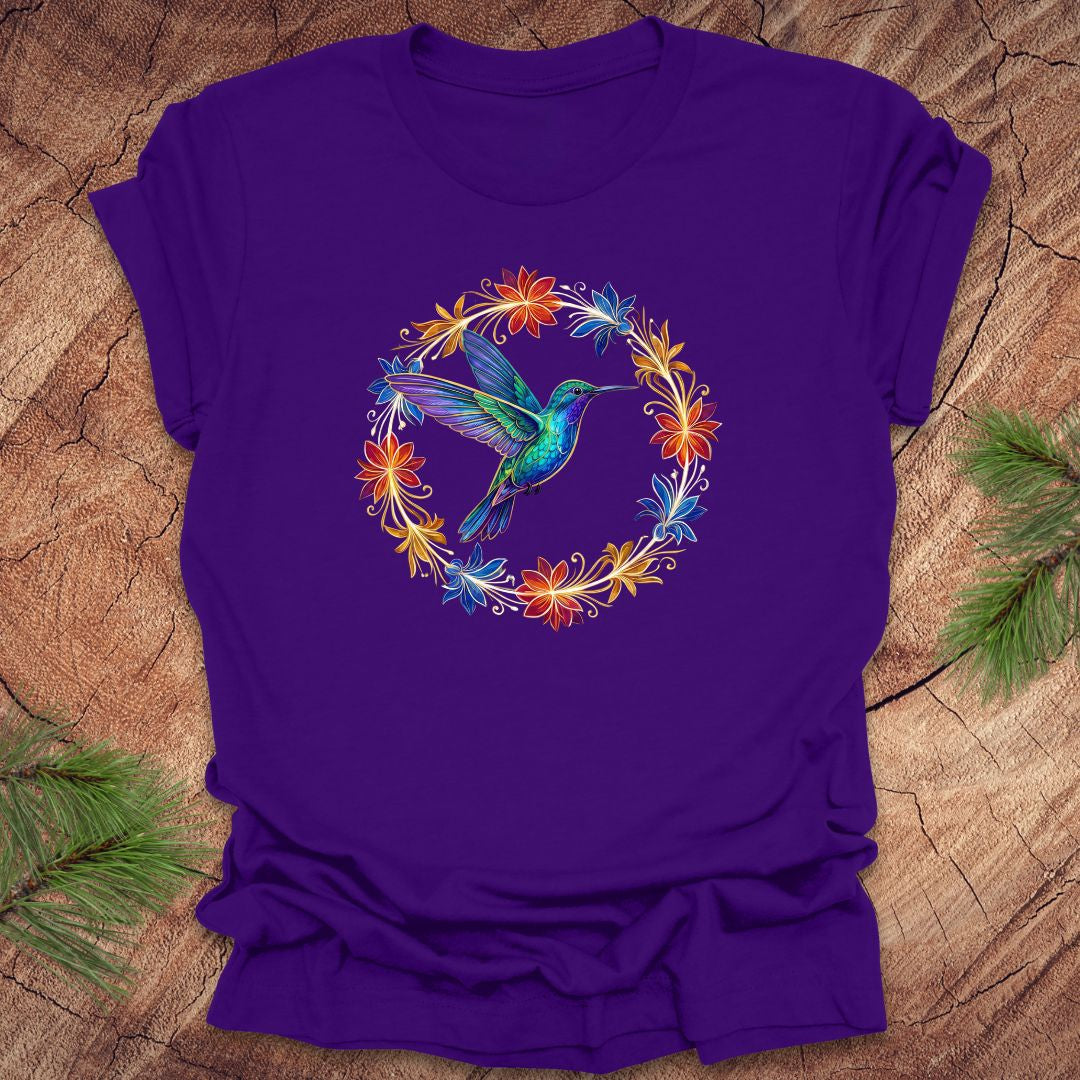 Purple t-shirt with a colorful hummingbird and floral design on a wooden surface.