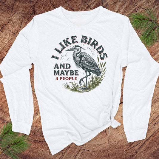 White long-sleeve t-shirt with a great blue heron and text on a wood background.